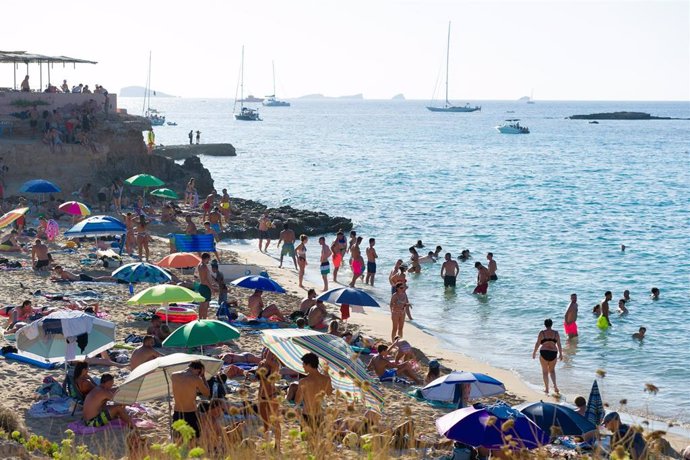 Bañistas disfrutan en la Cala Conta, a 9 de agosto de 2022, en Ibiza, Baleares (España). La Cala Conta está formada por finas y nacaradas arenas y aguas de un intenso color turquesa. Un entorno natural que la convierte en una de las mejores playas de Ib