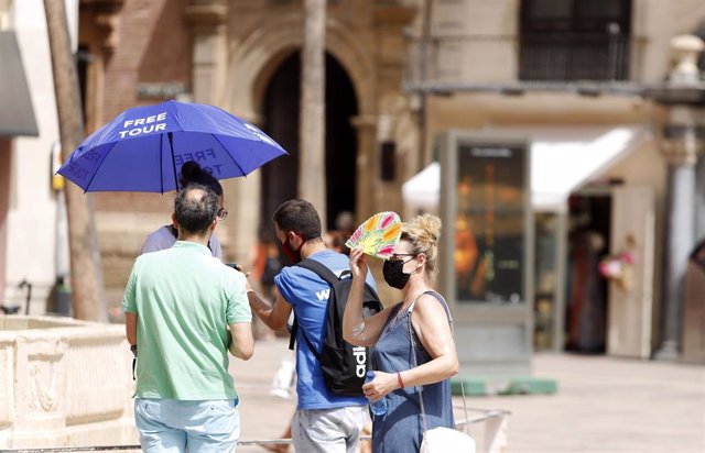 Archivo - Imagen de archivo de varias personas intentando protegerse del calor en Málaga