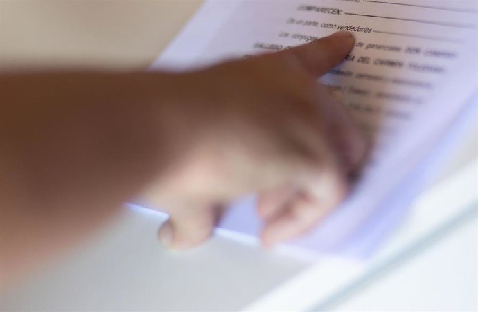 Archivo - Una mujer señala una escritura de compraventa de una hipoteca