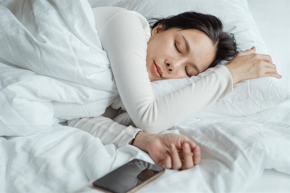 Una mujer descansando junto a un dispositivo móvil
