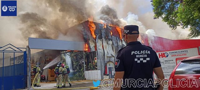 Efectivos trabajan en la extinciónde un incendio declarado en un establecimiento comercial situado en la rotonda que conecta la avenida Primero de Mayo y la avenida Arquitecto Miguel Ángel Beloqui, en el cruce de Las Atalayas, en Murcia.