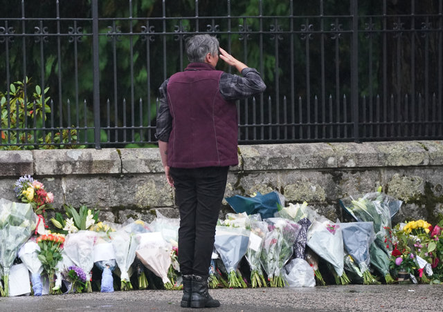 09 September 2022, United Kingdom, Balmoral: A member of the public salutes after laying flowers at the gates of Balmoral in Scotland following the death of Queen Elizabeth II on Thursday. Photo: Andrew Milligan/PA Wire/dpa