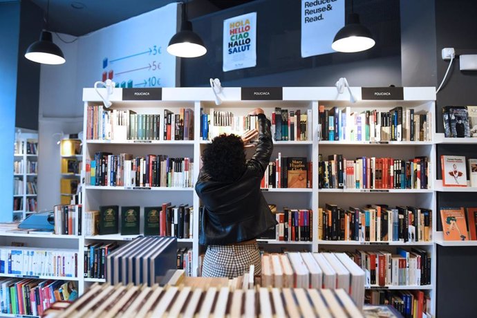 Archivo - Una mujer coloca libros en la librería de segunda mano