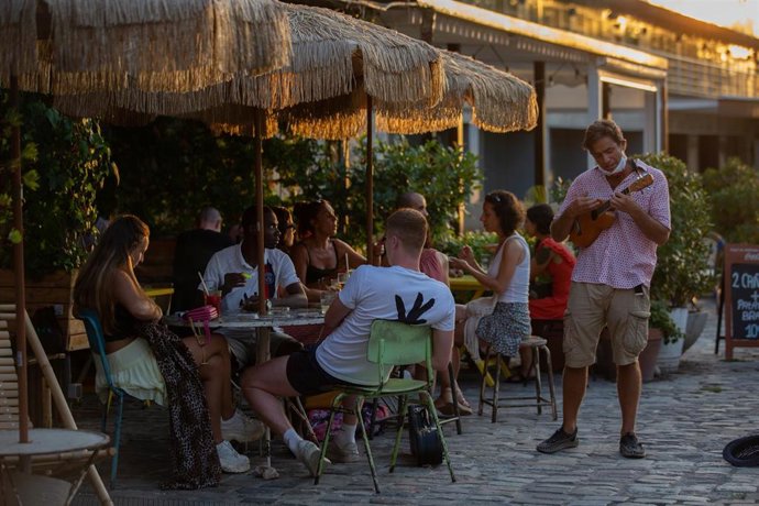 Archivo - Consumidores en terrazas junto a un artista callejero en Barcelona