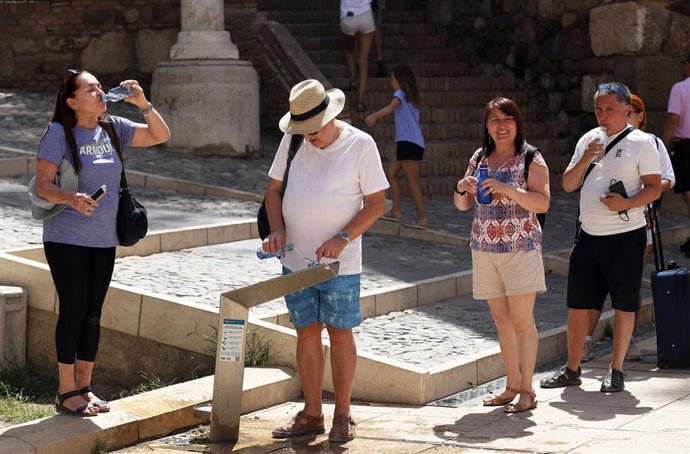 Archivo - Turistas beben agua para combatir el calor en una imagen de archivo