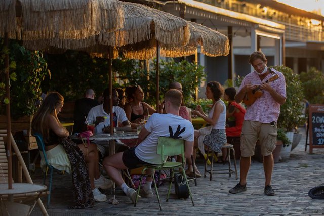 Archivo - Consumidors a les terrasses al costat d'un artista de carrer a Barcelona
