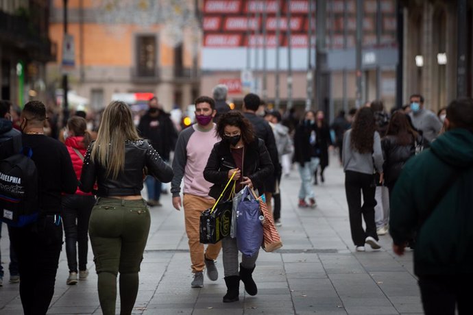 Archivo - Vianants caminen amb bosses per un carrer de Barcelona