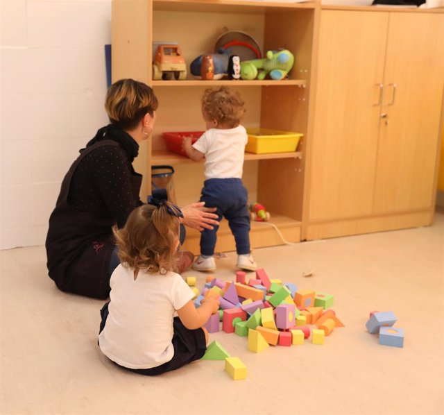 Varios niños juegan con la profesora en un aula de 0 a 3 años