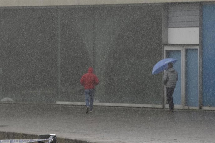 Archivo - Dos personas caminan por el paseo marítimo mientras llueve, a 8 de diciembre de 2021, en A Coruña, Galicia, (España). La borrasca Barra ha hecho que la Xunta haya activado para todo el litoral gallego una alerta naranja por temporal costero. S