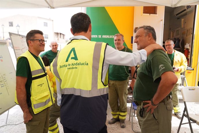 Visita de Juanma Moreno, de espaldas, al puesto de mando del incendio forestal de Los Guájares