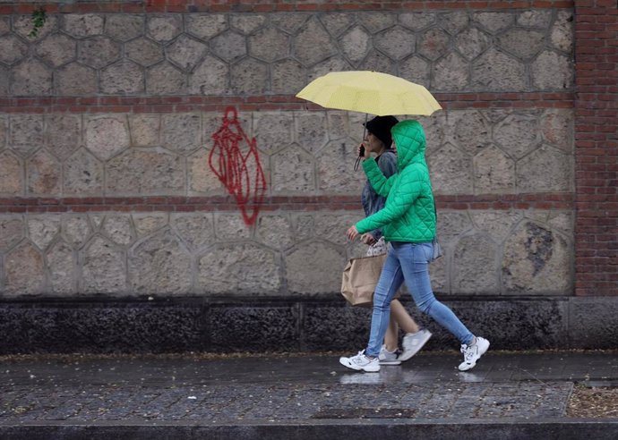 Archivo - Dos personas se protegen de la lluvia con un paraguas.