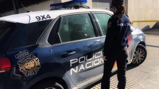 Un agente de la Policía Nacional de Valladolid junto a un coche patrulla.