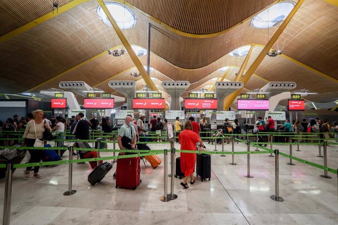 Varios pasajeros esperan para obtener sus tarjetas de embarque y facturar su equipaje, en la T4 del Aeropuerto Adolfo Suárez Madrid-Barajas, a 28 de agosto de 2022, en Madrid (España). 