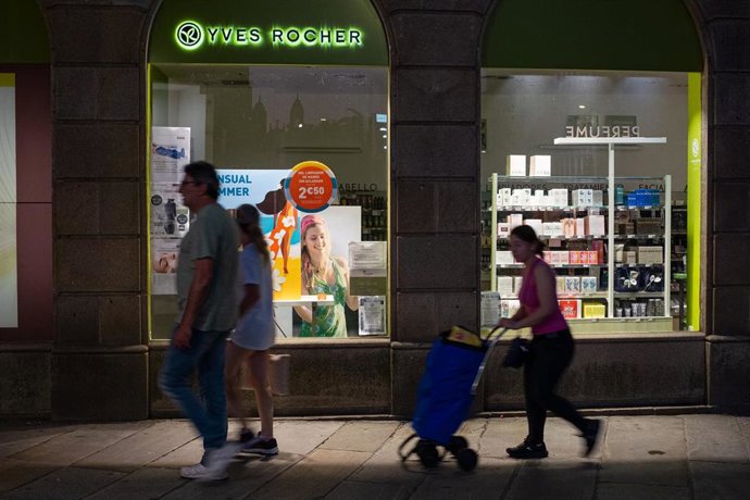 Archivo - Varias personas pasan por delante de una farmacia