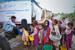 Unos niños esperan para recoger agua potable entregada por UNICEF y sus aliados en su aldea, en el distrito de Lasbela, provincia de Baluchistán (Pakistán).