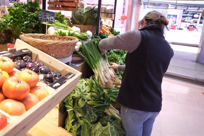 Archivo - Una mujer coloca los 'calots en su establecimiento de verduras.