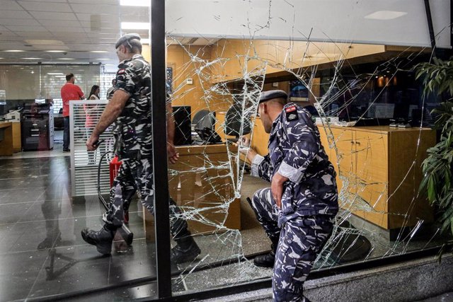 Un policía de Líbano entra en un banco a través de un agujero en una pared de cristal tras una toma de rehenes para exigir la entrega de ahorros ante las restricciones por la crisis
