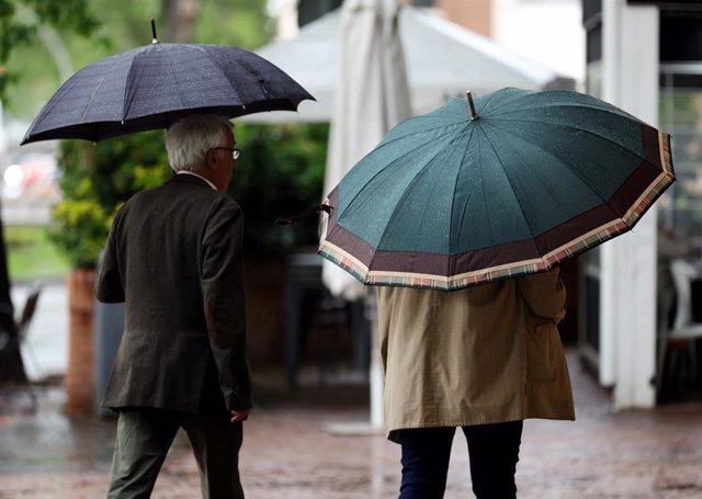 Archivo - Varias personas caminan con paraguas el día en que han puesto en aviso amarillo a la Comunidad de Madrid por tormentas y lluvias.