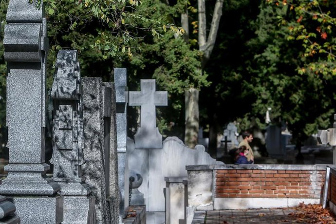 Archivo - Dos personas caminan por un cementerio