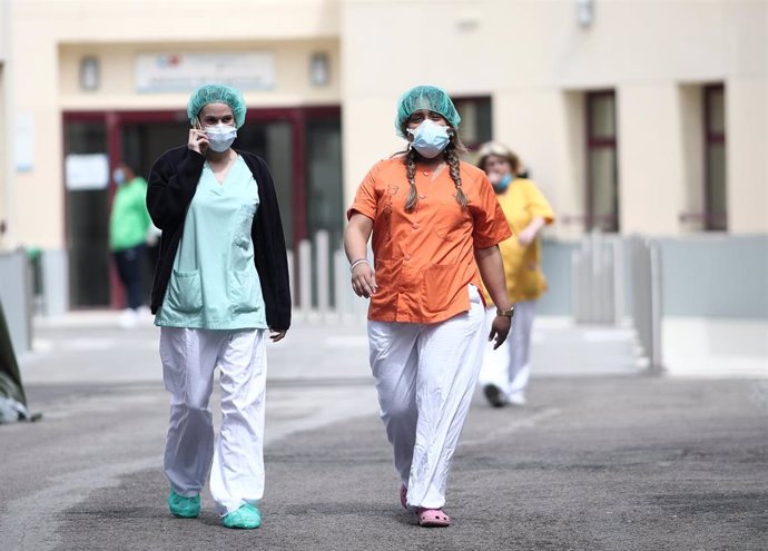 Archivo - Dos sanitarias protegidas con mascarilla y gorro caminan cerca del Hospital de campaña en las inmediaciones de las Urgencias del Gregorio Marañón para la lucha contra el coronavirus, en Madrid (España) a 6 de abril de 2020.