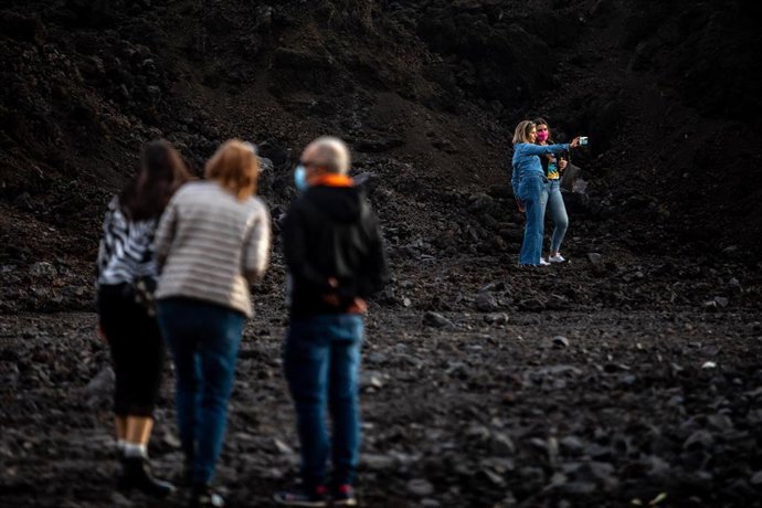Archivo - Una pareja de turistas se hacen un 'selfie' sobre la colada de lava del volcán de Cumbre Vieja