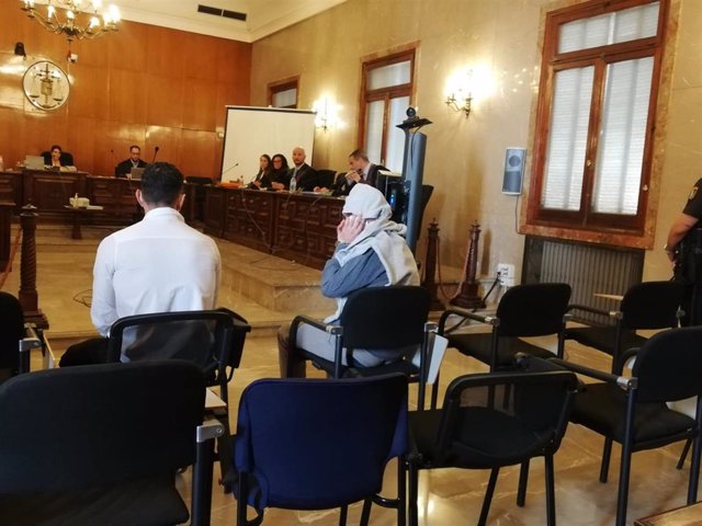 Uno de los acusados por el incendio de un edificio 'okupa' de Ibiza se tapa la cara con las manos y una sudadera ante las cámaras, momentos antes de comenzar el juicio en la Audiencia Provincial.