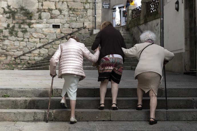 Archivo - Personas mayores caminan por una calle en Galicia. Alivio familiar.