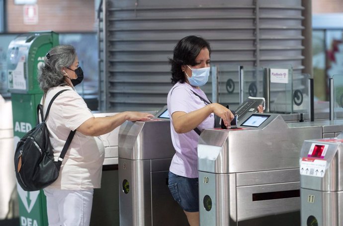 Varios viajeros pasan su título de viaje por el lector óptico en la estación de tren de Atocha