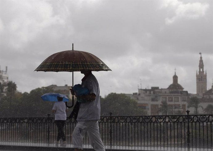 Dos personas caminan bajo sus paraguas en Sevilla (Foto de archivo).