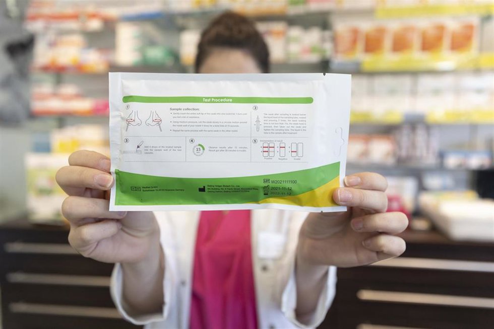 Archivo - Una farmacéutica muestra un test de antígenos 