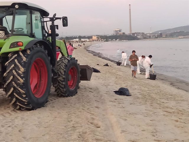 Trabajadores limpiando el vertido en la playa de El Rinconcillo.