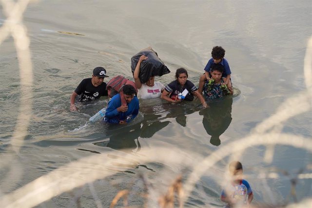 Archivo - Un grupo de personas intena cruzar a Estados Unidos a través de río Grande, en México.
