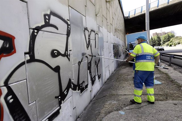 Archivo - Un operario limpia grafitis durante el comienzo de la campaña de limpieza de grafitis en Calle 30.