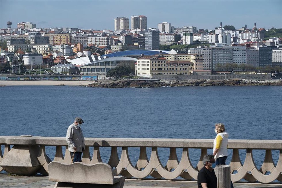 Archivo - Dos personas pasean por el paseo marítimo de A Coruña (Galicia), con el estadio de Riazor de fondo