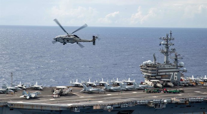 Archivo - 02 August 2022, ---, --: Cmdr. Nick Cunningham, commanding officer of the 'Saberhawks' of Helicopter Maritime Strike Squadron (HSM) 77 flies over the flight deck of the US Navy's only forward-deployed aircraft carrier USS Ronald Reagan (CVN 76