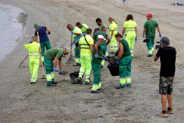 Operarios limpiando la playa en La Línea tras la llegada de vertido procedente del OS35.