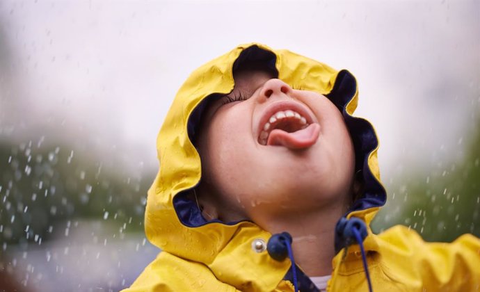Niño disfrutando bajo la lluvia.