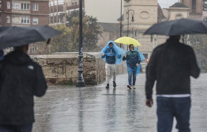 Archivo - Imatge de recurs de persones amb paraigües i impermeables que caminen sota la pluja