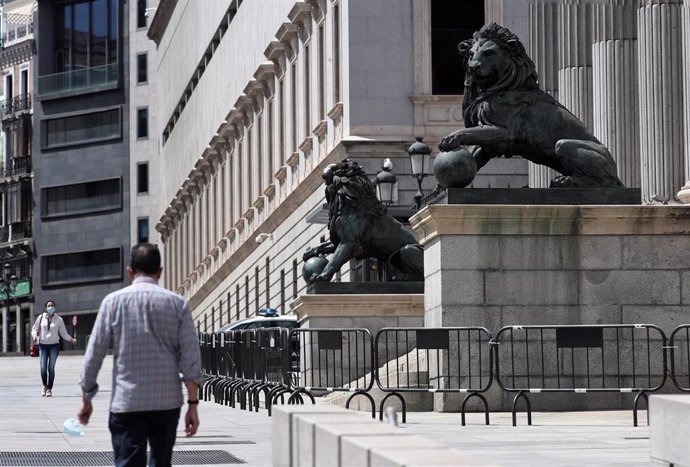 Archivo - Varias personas pasan por delante de la fachada del Congreso de los Diputados, que este miércoles vota por cuarta vez una prórroga del estado de alarma decretado frente al coronavirus, que no tiene riesgo de revocarse mientras el PP no vote en