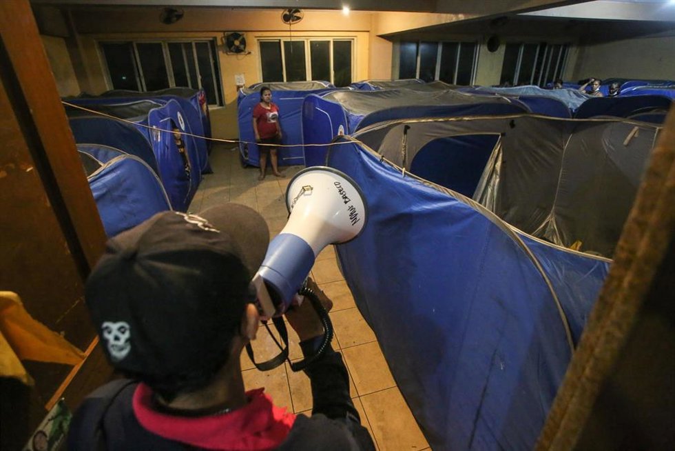Un voluntario recuerda a los evacuados a cumplir los protocolos de seguridad tras el supertifón 'Noru', Baseco, Filipinas.