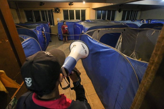 25 September 2022, Philippines, Baseco: A volunteer with a megaphone reminds evacuees of safety protocols after people arrive at an evacuation center. Photo: Earvin Perias/ZUMA Press Wire/dpa