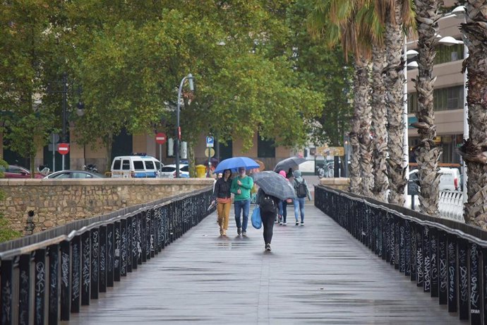Archivo - Varias personas pasean por una calle de Valncia, con paraguas (archivo)