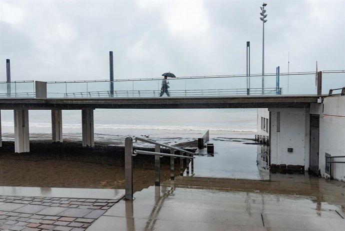 Una persona se refugia de la lluvia bajo paraguas un cerca de la playa