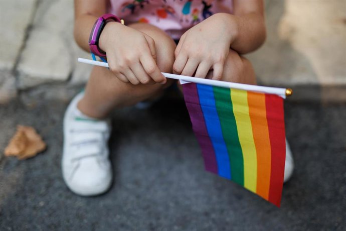 Archivo - Una niña sostiene la bandera del arcoiris minutos antes del inicio de una manifestación por el Orgullo LGTBIQ+.