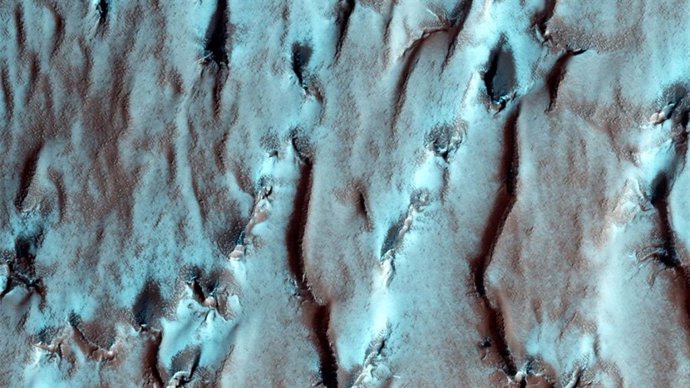 Esta imagen del Orbitador de Reconocimiento de Marte (MRO) de la NASA muestra el borde del depósito en capas del Polo Sur marciano. La pila de capas finas se destaca por los rayos del sol polar.