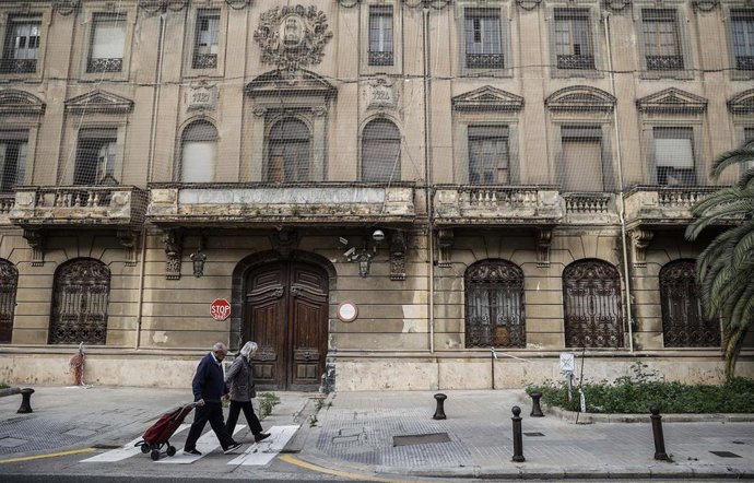 Archivo - Dos personas caminan frente a los exteriores del edificio del complejo policial de Zapadores en el barrio de Russafa