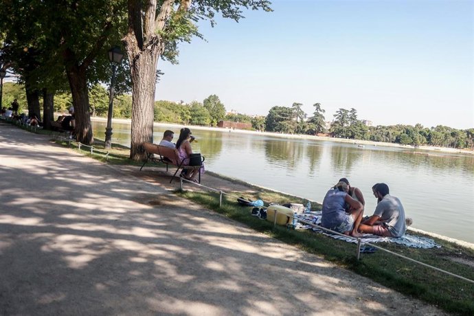 Archivo - Varias personas sentadas en la orilla del lago de la Casa de Campo, en Madrid (España).