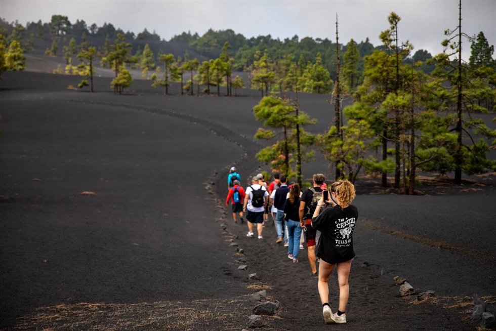 Turistas caminan por un sendero afectado por la lava del volcán de Tajogaite, en la Sierra de Cumbre Vieja, La Palma, Canarias