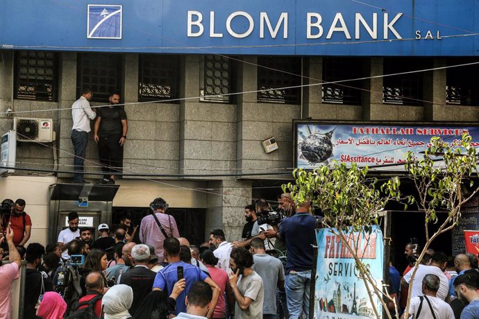 16 September 2022, Lebanon, Beirut: Lebanese activists gather outside a local bank, after depositor Abed Soubra stormed the branch demanding access to his deposits. Lebanese police on Friday  detained an armed man who entered a bank south of Beirut dema