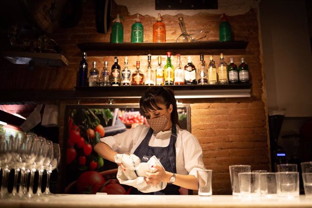 Archivo - Una camarera seca unos vasos en el interior de un bar en una calle céntrica de Barcelona, a 14 de octubre de 2021, en Barcelona, Catalunya (España).  